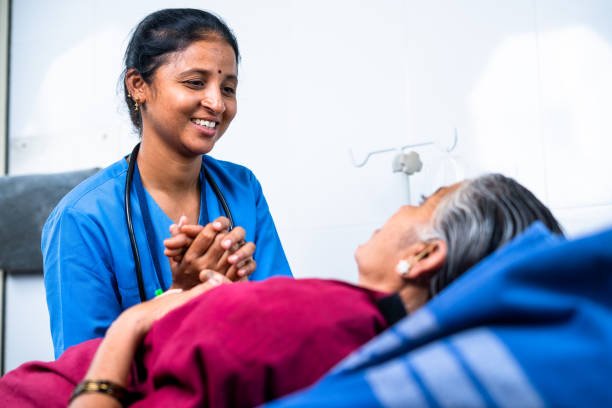 happy smiling Nurse consoling elderly senior patient after surgery at hospital on bed - concept of caring, medical treatment and healthcare service.